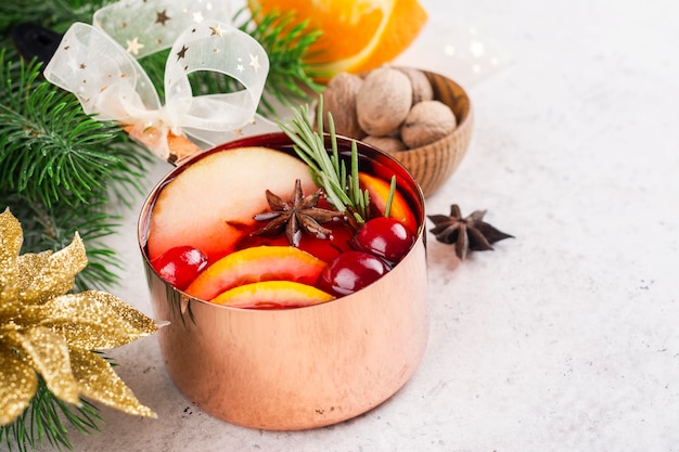 Vino caliente caliente con frutas y especias en una olla de cobre