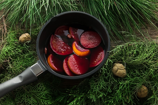 Vino caliente caliente en una olla con asas y una pala de cocina de hierro.