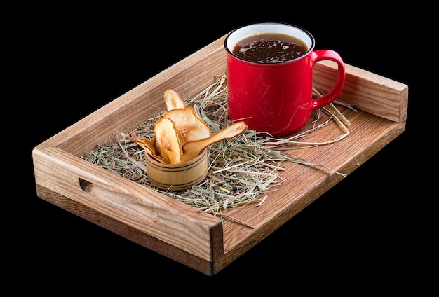 Vino caliente caliente con una taza de metal sobre una tabla de madera con paja y chips de manzana