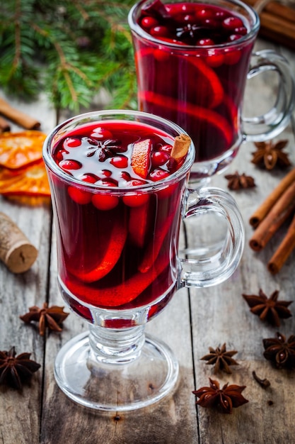 Vino caliente casero con rodajas de naranja, arándanos, canela y anís sobre mesa de madera