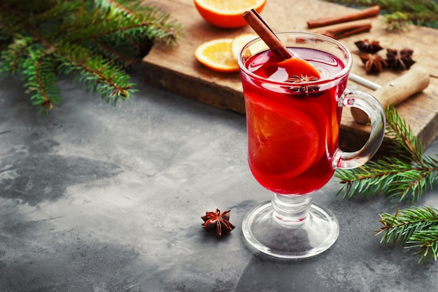 Vino caliente con especias y árbol de navidad en la oscuridad