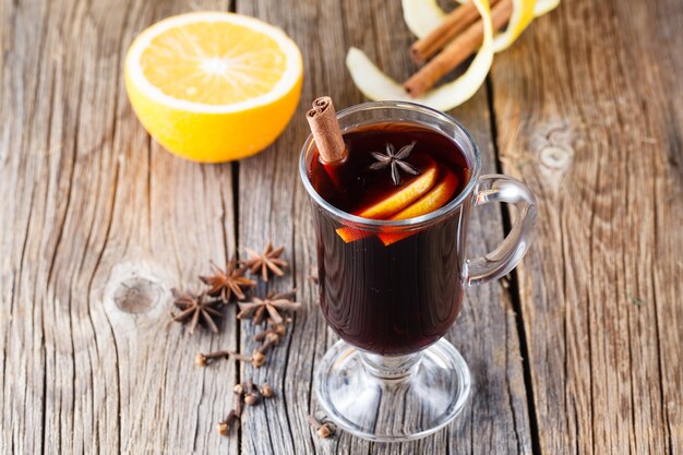 Vino caliente y especias en una mesa de madera desgastada