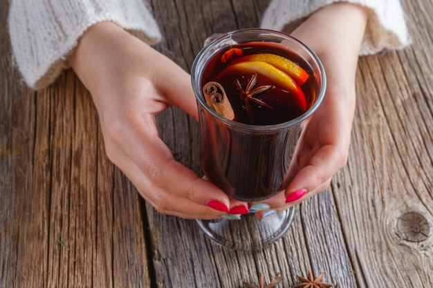 Vino caliente y especias en una mesa de madera desgastada