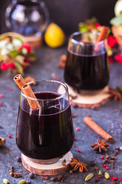 Vino caliente con especias en vasos de vidrio Vino caliente con canela y anís estrellado sobre una mesa azul