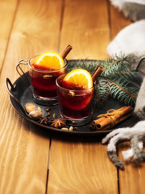 Vino caliente festivo de Navidad con especias en vasos de vidrio sobre una mesa de madera.