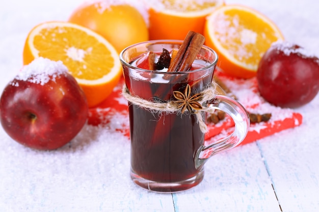 Vino caliente fragante en vidrio en primer plano de la nieve