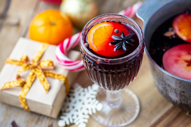 Vino caliente en un hermoso vaso junto a la cacerola. Bebida caliente en un vaso. Concepto de navidad. Noche familiar con una bebida caliente.