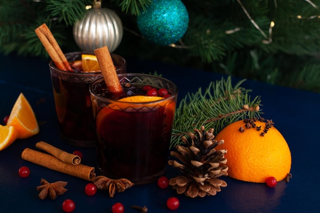 Foto vino caliente de navidad con canela, naranja, anís y clavo con sombras de la luz del sol sobre un fondo azul. vacaciones de invierno.