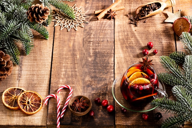 Vino caliente de Navidad con especias sobre una mesa rústica de madera.