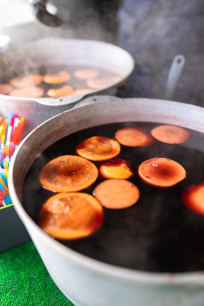 Vino caliente de Navidad en la feria elaborado en un caldero con canela y cítricos Cocinando una bebida tradicional de Navidad y Año Nuevo