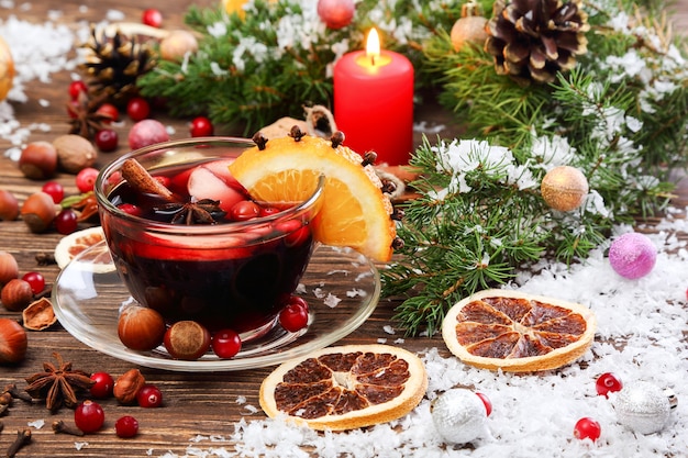 Vino caliente de Navidad con manzana, arándano, naranja y especias en una mesa de madera