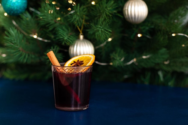 Foto vino caliente navideño con canela, naranja, anís y clavo sobre un fondo azul. vacaciones de invierno.