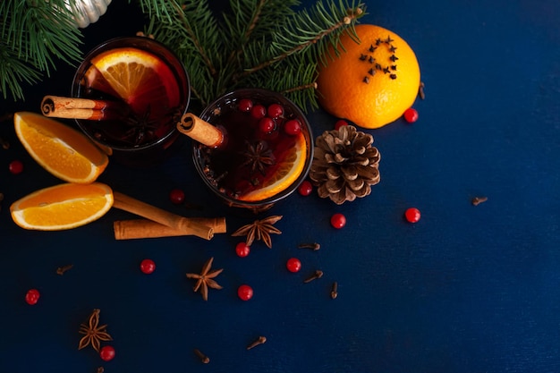 Foto vino caliente navideño con canela, naranja, anís y clavo sobre un fondo azul. vacaciones de invierno.