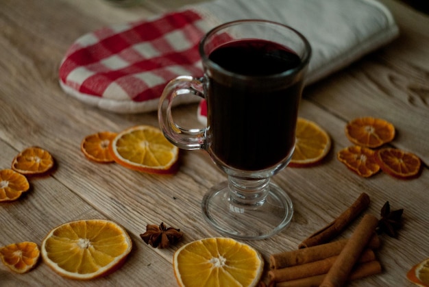 Vino caliente y rodajas de naranja secas en la mesa