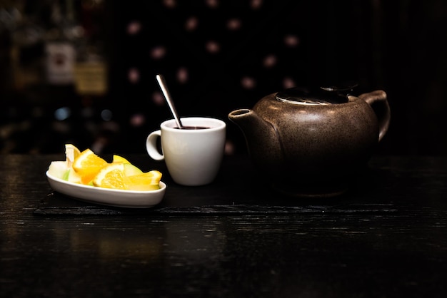 Vino caliente sangría vino caliente en una copa blanca sobre un fondo oscuro barra de bar con té de frutas y especias palitos de canela y naranja