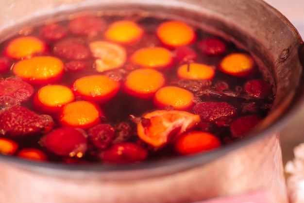 Vino caliente tradicional, bebida callejera de invierno, preparado y calentado en una olla en invierno en una calle