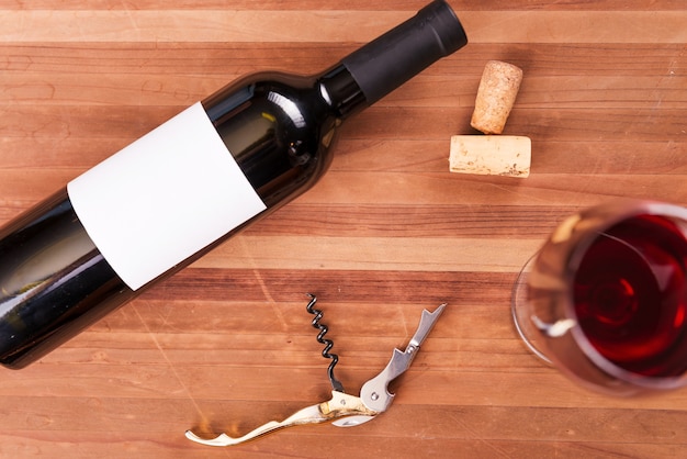Vino en detalles. Vista superior de la botella y copa de vino con vino tinto en la mesa de madera
