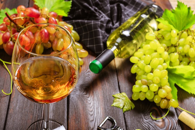 Vino con ramas de uvas blancas. En una mesa de madera.