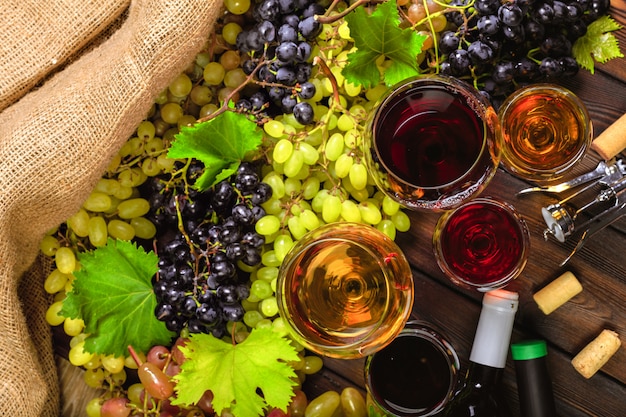 Vino con ramas de uvas blancas. En una mesa de madera.