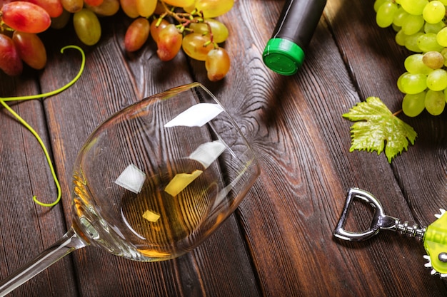 Foto vino con ramas de uvas blancas. sobre una mesa de madera.