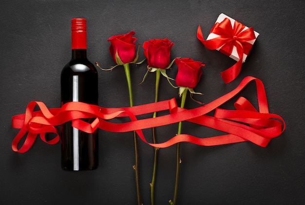 Vino, rosas y caja de regalo con un lazo rojo. Concepto de amor