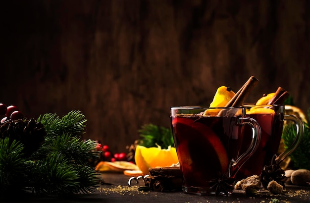 Vino tinto caliente caliente de Navidad con especias y frutas en una mesa rústica de madera Bebida caliente tradicional de Navidad en una mesa festiva