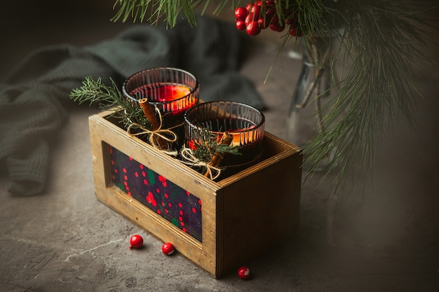 Vino tinto caliente de Navidad con especias aromáticas y frutas cítricas en caja de madera, primer plano. Bebida caliente tradicional en Navidad