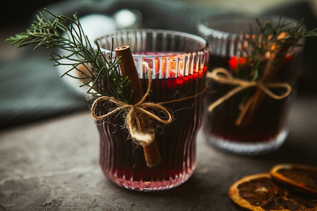 Vino tinto caliente de Navidad con especias aromáticas y frutas cítricas en superficie negra, primer plano. Bebida caliente tradicional en Navidad