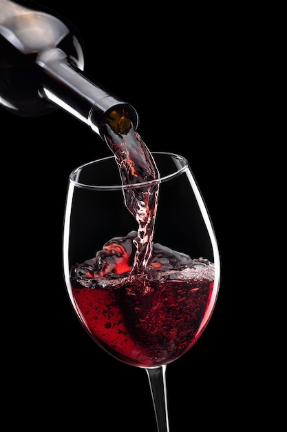 vino tinto derramado en un vaso de botella aislado sobre un fondo negro