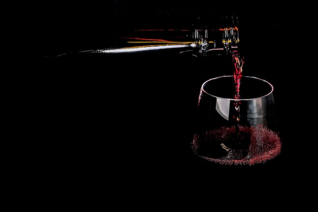 El vino tinto fortificado se vierte en una fotografía de arte de copa de vidrio sobre un fondo negro de cerca