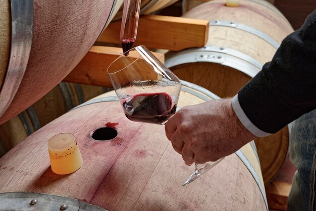 Vino tinto de Italia Sicilia vertido de un barril de madera en un vaso en una bodega