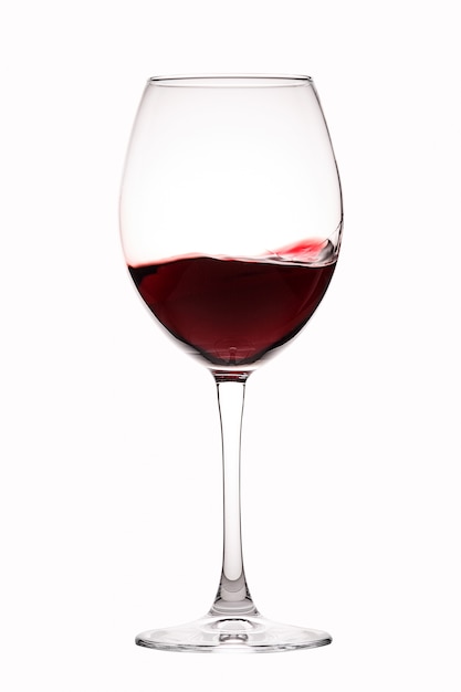 Foto vino tinto salpica en un vaso sobre blanco