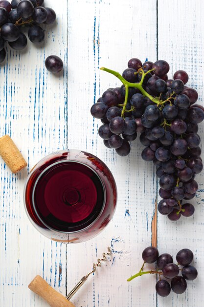 Vino tinto y uvas. Vino y uvas en ambiente vintage con corchos en mesa de madera