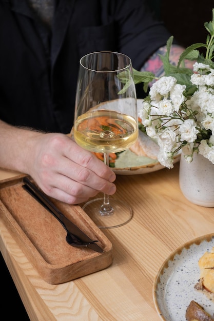 Vino en un vaso en la mano de un hombre en una mesa de un restaurante