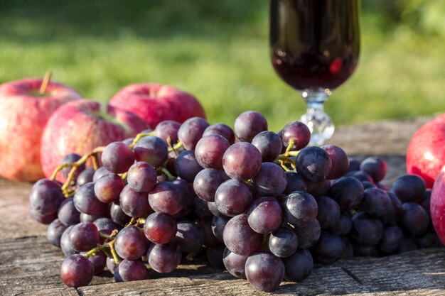 Foto vino en un vaso y uvas en una mesa de madera.