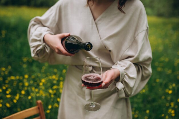 Vino vertido de una botella de picnic al aire libre Verter vino tinto en una copa en el jardín