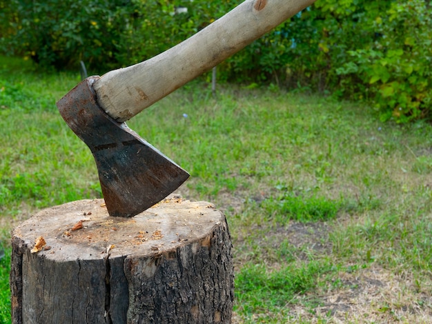 Vintage antiguo hacha clavada en un tronco de madera utilizado para picar otros troncos de madera