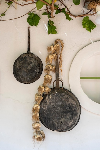 Vintage Bratpfanne und Bund Knoblauch auf einer weißen Wand in der Nähe der Insel Kos Griechenland