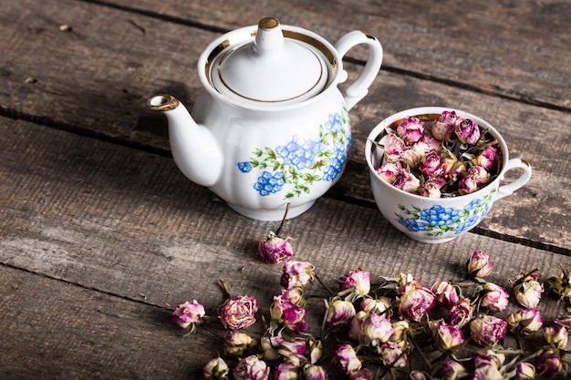 Vintage bule e xícara com flores desabrochando de chá na madeira