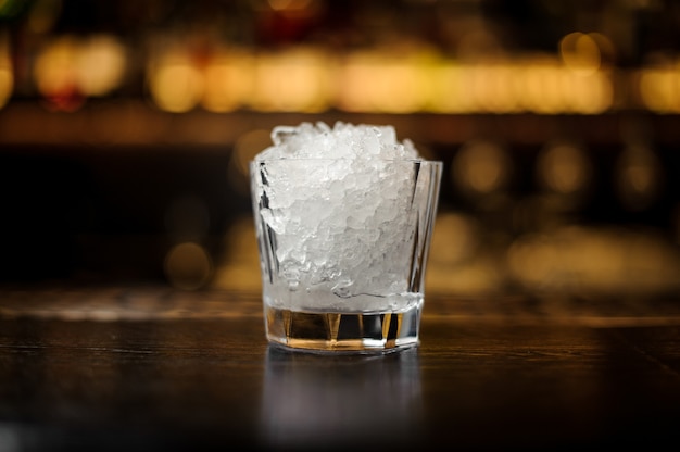 Vintage-Cocktailglas mit zerstoßenem Eis, das auf dem leeren Barständer aus Stahl steht