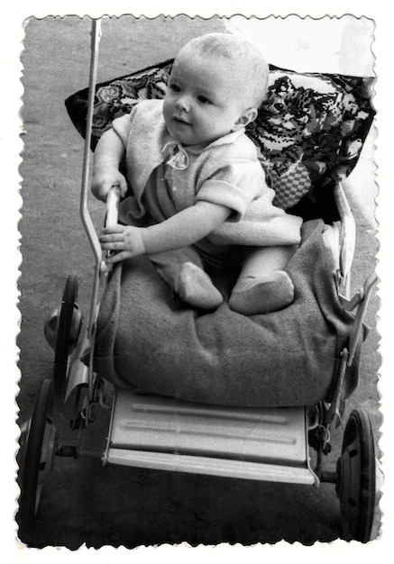 Vintage-Foto eines Jungen in einem Kinderwagen Das lächelnde Kind Foto aus 1961