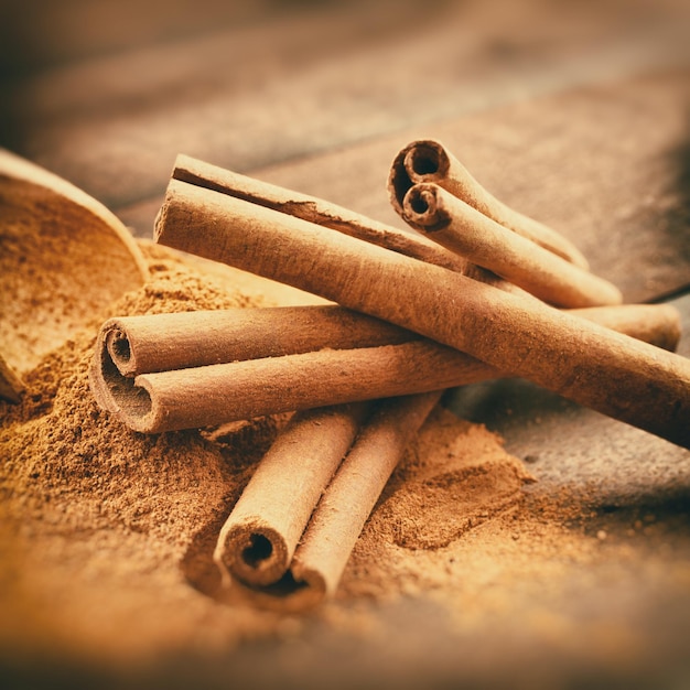 Vintage foto estilizada de palitos de canela y polvo de canela en tablón de madera