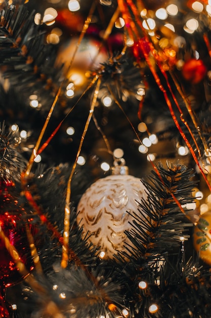 Vintage goldene Weihnachtskugel mit goldenem Glitter und rotem Retro-Dekor, die am Weihnachtsbaum hängen