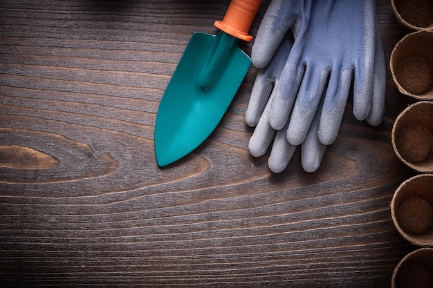 Vintage-Holzplatte mit Schutzhandschuhen, verschiedene Torftöpfe und Handspaten-Gartenkonzept