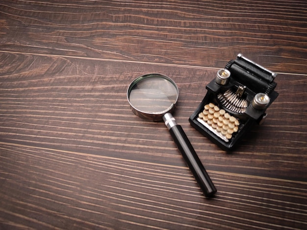 Foto vintage máquina de escribir negra y lupa sobre un fondo de madera