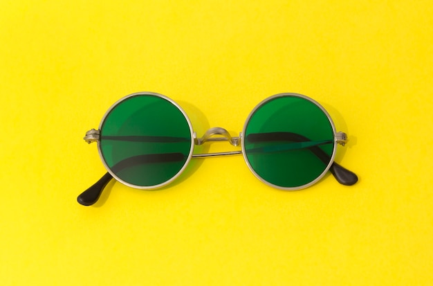 Vintage modische runde grüne Sonnenbrille auf gelbem Tisch