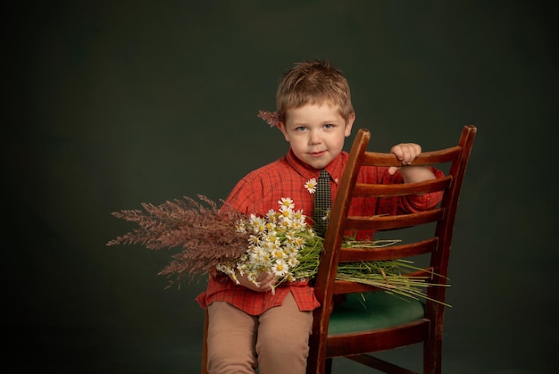 Vintage Portrait des kleinen Jungen mit wilden Blumen auf grünem Hintergrund