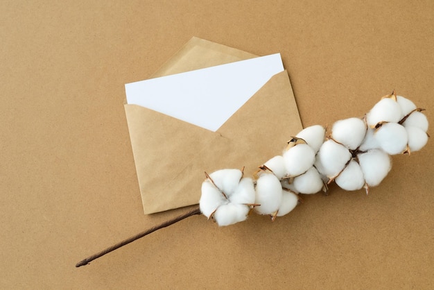 Vintage Postumschlag der leeren Karte auf Kraftpapierhintergrund mit Baumwollblumenniederlassungs-Kopienraum