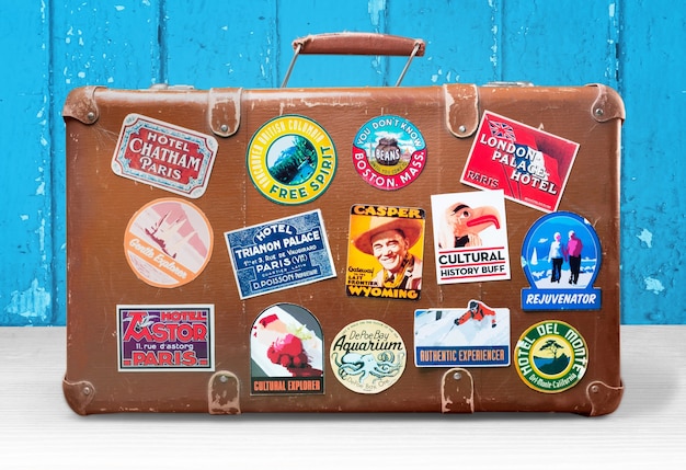 Foto vintage reisetasche mit aufklebern auf dem hintergrund