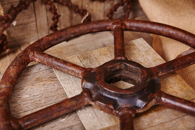 Vintage-Rostmetallrad auf verwittertem Holz mit industriellem Kettengrund